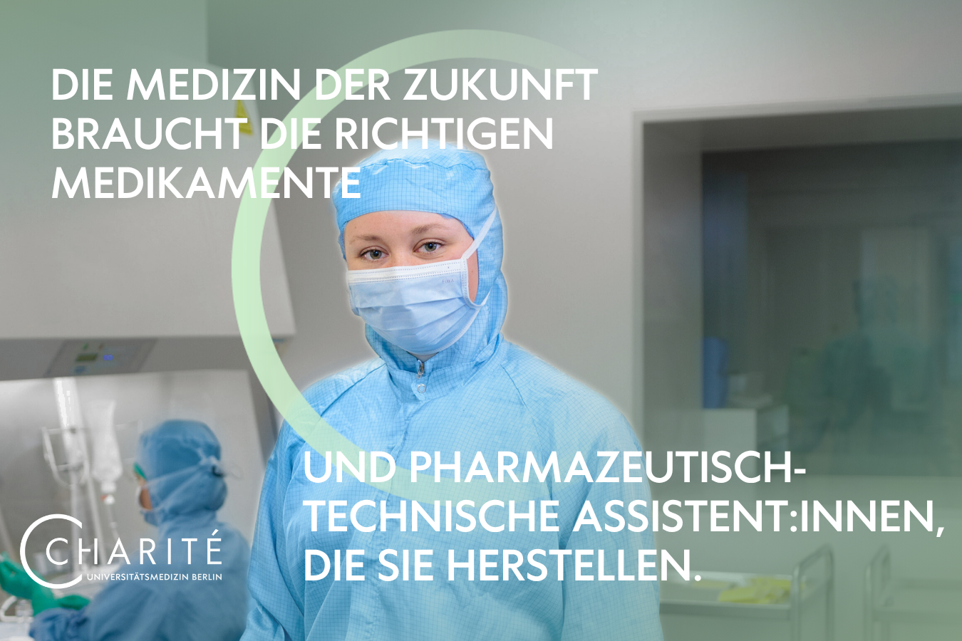 Eine PTA der Charite in voller Schutzausrüstung an ihrem Arbeitsplatz, die in die Kamera guckt.
