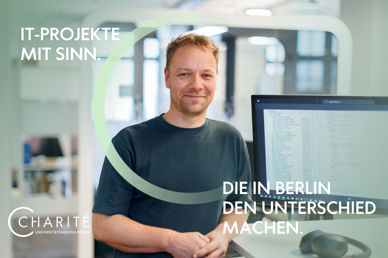 Charite IT Motiv 6 - Projekte mit Sinn, die in Berlin den Unterschied machen. Ein Projektmanager des IT-Bereichs steht am Schreibtisch und blickt in die Kamera