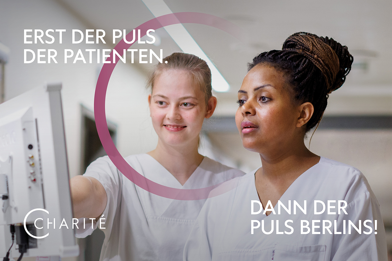 Azubi-Kampagnenmotiv: Zwei Frauen stehen an einem Bildschirm auf einem Krankenhausflur und sprechen miteinander. Auf dem Bild steht - Erst der Puls der Patienten, dann der Puls der Stadt -