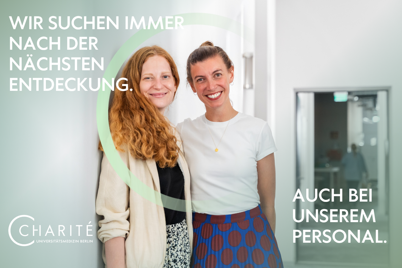 Zwei Charite Kolleginnen stehen im Flur und lächeln in die Kamera