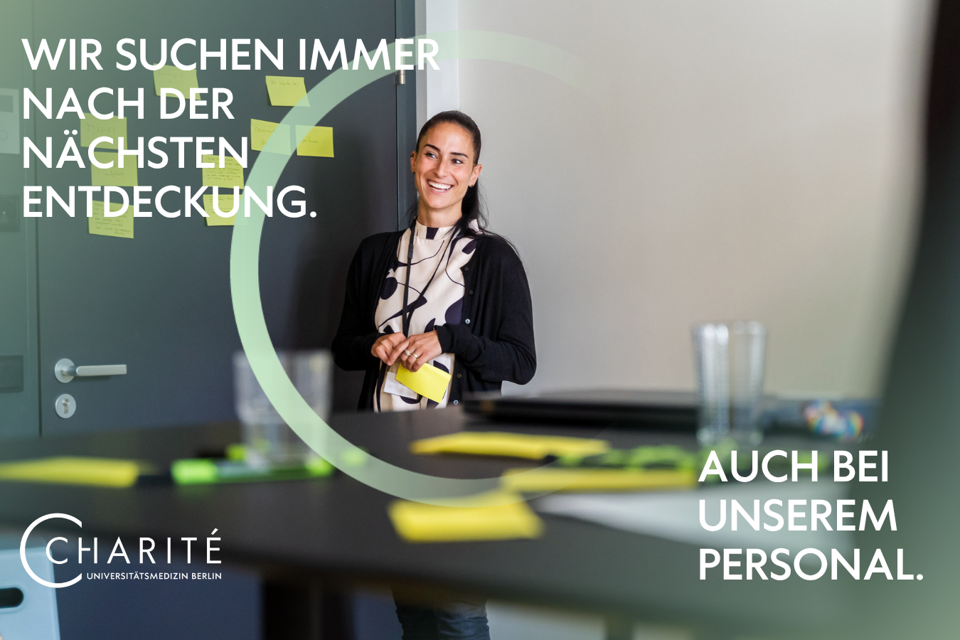 Eine Charite Kollegin steht vor einer Wand mit Post-its und lächelt in die Kamera